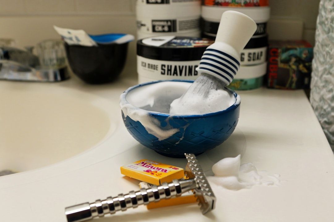 Brotxa d'afaitar amb escuma i navalla sobre la pica